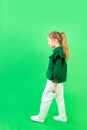 A girl of 8 years old goes forward on a green background, step forward, space for text Royalty Free Stock Photo