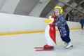 girl 3 years old learn to skate on an indoor Ice skating rink. A plastic penguin is being pushed by skating girl for Royalty Free Stock Photo