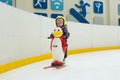 girl 3 years old learn to skate on an indoor Ice skating rink. A plastic penguin is being pushed by skating girl for Royalty Free Stock Photo