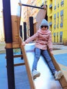 The girl 9 years old on the playground. The child is dressed in warm demi-season clothes a pink jacket and a grey hat. Royalty Free Stock Photo