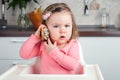 Girl 2 years old playing with a comb at home - portraying an emotional conversation on the phone.
