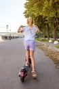 A girl of 8 years old rides an rented electric scooter in the park