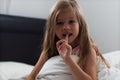 Girl 6 years old shows shaky milk tooth sitting on bed after sleep