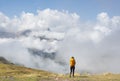 Girl with yellow backpack hiking in the Pyrenees, with the mountains in the clouds in the background Royalty Free Stock Photo