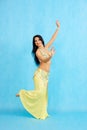 Charming dancer performs oriental belly dance on a blue background.