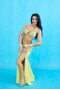 Charming dancer performs oriental belly dance on a blue background.