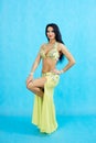 Charming dancer performs oriental belly dance on a blue background.