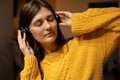 girl In yellow casual sweater closed eyes enjoys to music with headphones
