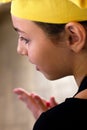 Girl in the yellow chef`s cap and black apron gaily looks to the Royalty Free Stock Photo