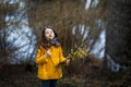 A girl in a yellow coat in the forest in early spring with a willow branch of twigs. A girl furing freshet or high water