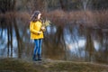 A girl in a yellow coat in the forest in early spring with a willow branch of twigs. A girl furing freshet or high water