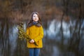 A girl in a yellow coat in the forest in early spring with a willow branch of twigs. A girl furing freshet or high water