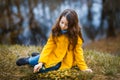 A girl in a yellow coat in the forest in early spring with a willow branch of twigs. A girl furing freshet or high water