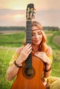 girl in yellow dress bohemian style, holding a guitar on the field
