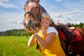 Girl in yellow dress with a horse on a green field and a blue sky with white clouds on the background Royalty Free Stock Photo