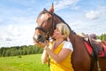 Girl in yellow dress with a horse on a green field and a blue sky with white clouds on the background Royalty Free Stock Photo