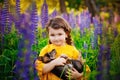 A girl in a yellow dress hugs a puppy in the nature, summer landscape. A child with a dog in a meadow among the tall blue flowers