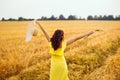 A girl in a yellow dress with long dark hair enjoys life whirling and dancing in a wheat field in the warm sunset light