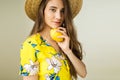 Girl in yellow dress and hat holds lemon