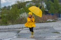 Girl in a yellow dress with an umbrella joyful spring runs through the puddles on a rainy day Royalty Free Stock Photo