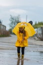 Girl in a yellow dress with an umbrella joyful spring runs through the puddles on a rainy day Royalty Free Stock Photo