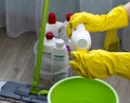 A girl in yellow gloves pours a cleanser in a green bucket, close-up cleaner