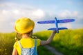 Girl in a yellow hat launches a toy plane into the field, looks at the trail. Summer time, childhood, dreams and carelessness. Air