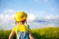 Girl in a yellow hat launches a toy plane into the field, looks at the trail. Summer time, childhood, dreams and carelessness. Air Royalty Free Stock Photo