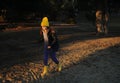 A girl in a yellow hat and rubber boots walks through the forest. Travel concept with children. Royalty Free Stock Photo