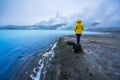 Girl with yellow hiking jacket stands on volcanic rock looking towards Geothermal powerplant at the blue lagoon in Jarabodin/Myvat Royalty Free Stock Photo