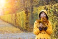 Girl in a yellow hooded coat holds the leaves in her hands Augarten park Vienna autumn