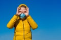 A girl in a yellow jacket with a hood and a blue medical mask. Royalty Free Stock Photo