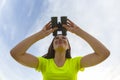 Girl in a yellow jacket looking through binoculars against the sky Royalty Free Stock Photo