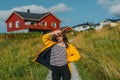 Girl in yellow jacket on the pathway to houses on Lofoten Islands