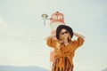 A girl in a yellow-orange suit on the beach against the background of the sea, mountains and a lighthouse. Fashionable woman in