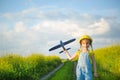 Girl in a yellow panama hat launches a toy plane into the field. Summer time, happy childhood, dreams and carelessness. Air tour