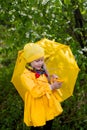 Girl in a yellow raincoat, a yellow hat with a yellow umbrella on a sunny spring day Royalty Free Stock Photo
