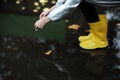 A girl in a yellow rubber boots walks through the forest. Travel concept with children. Autumn in the forest. Royalty Free Stock Photo