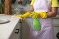 The girl in yellow rubber gloves and an apron removes. Hand wipes the table surface and holds the spray Royalty Free Stock Photo