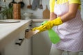 The girl in yellow rubber gloves and an apron removes. Hand wipes the table surface and holds the spray Royalty Free Stock Photo