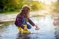 A girl in yellow sopog plays in a puddle in a small boat and makes spray