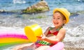 Girl in yellow straw hat plays with the wind, water and a water dispenser in an inflatable pool on the beach. Indelible products Royalty Free Stock Photo