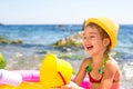 Girl in yellow straw hat plays with the wind, water and a water dispenser in an inflatable pool on the beach. Indelible products Royalty Free Stock Photo