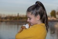 Girl with a yellow sweater hugging a teddy near a lake