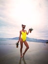 A girl in a yellow swimsuit in sunglasses stands by the sea in Nha Trang Vietnam. pineapples in hand.