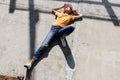 The girl in yellow t-shirt, jeans and pink visor is laying on a concrete slab on a sunny day outside