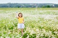 A girl in a yellow T-shirt and a wreath of daisies on her head plays in nature with soap bubbles. A child in a blooming chamomile