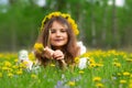 Girl with yellow wreath is laying in dandelions and violets in spring Royalty Free Stock Photo