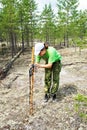 Girl zoologist sets camera trap for observing wild animals in taiga forest to collect scientific data. Environmental protection, Royalty Free Stock Photo