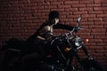 Female model on motorcycle in darkness over brick wall Royalty Free Stock Photo